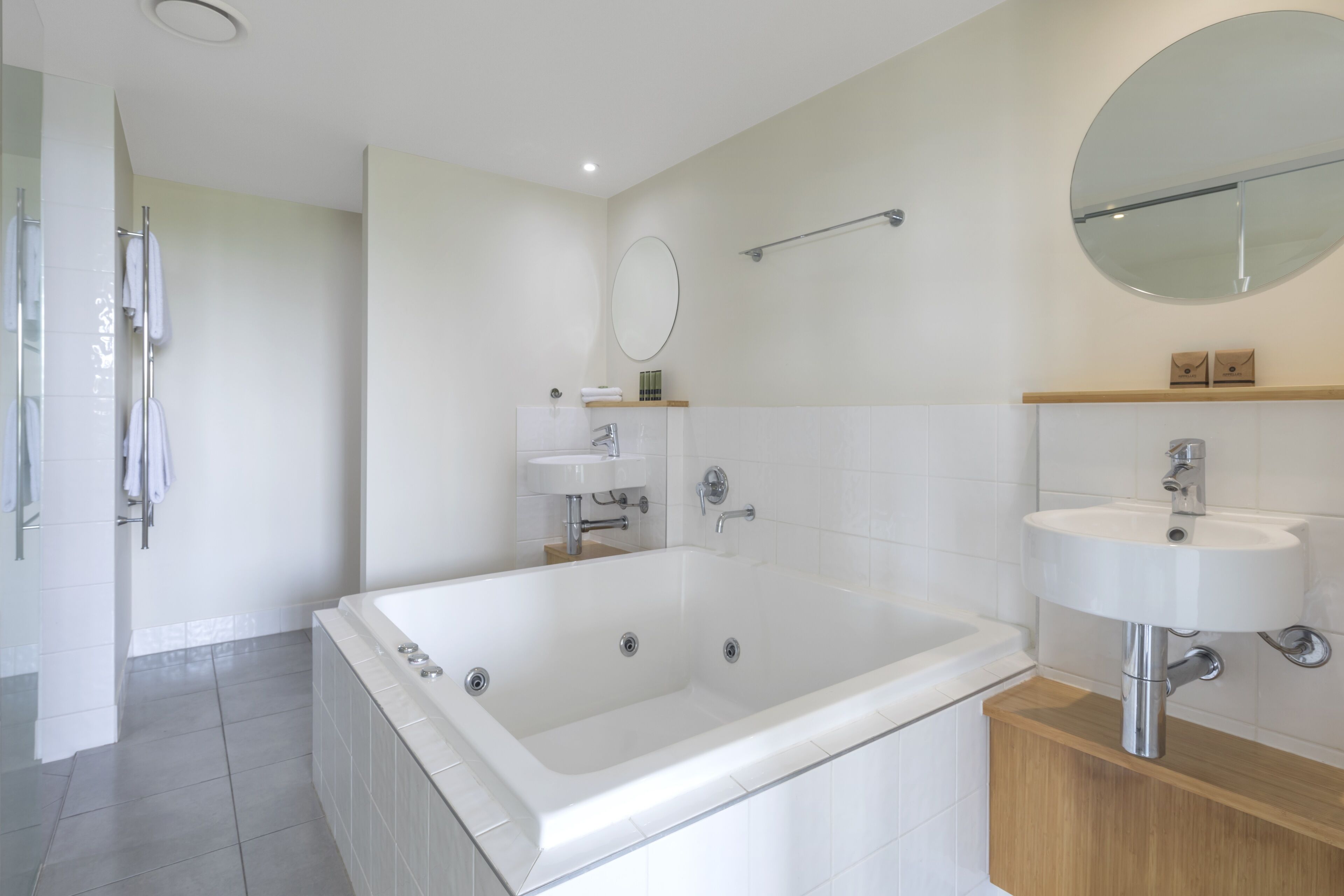 A modern bathroom with a large bathtub, a sink, and a mirror.