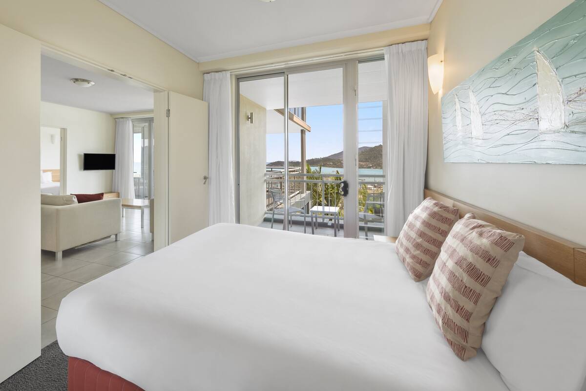 Una habitación de hotel con una cama grande, un balcón con vistas y un cuadro en la pared.
