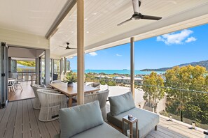 A spacious balcony with a view of the sea and mountains, furnished with wicker chairs and a sofa. - Club Wyndham Airlie Beach (Airlie Beach)
