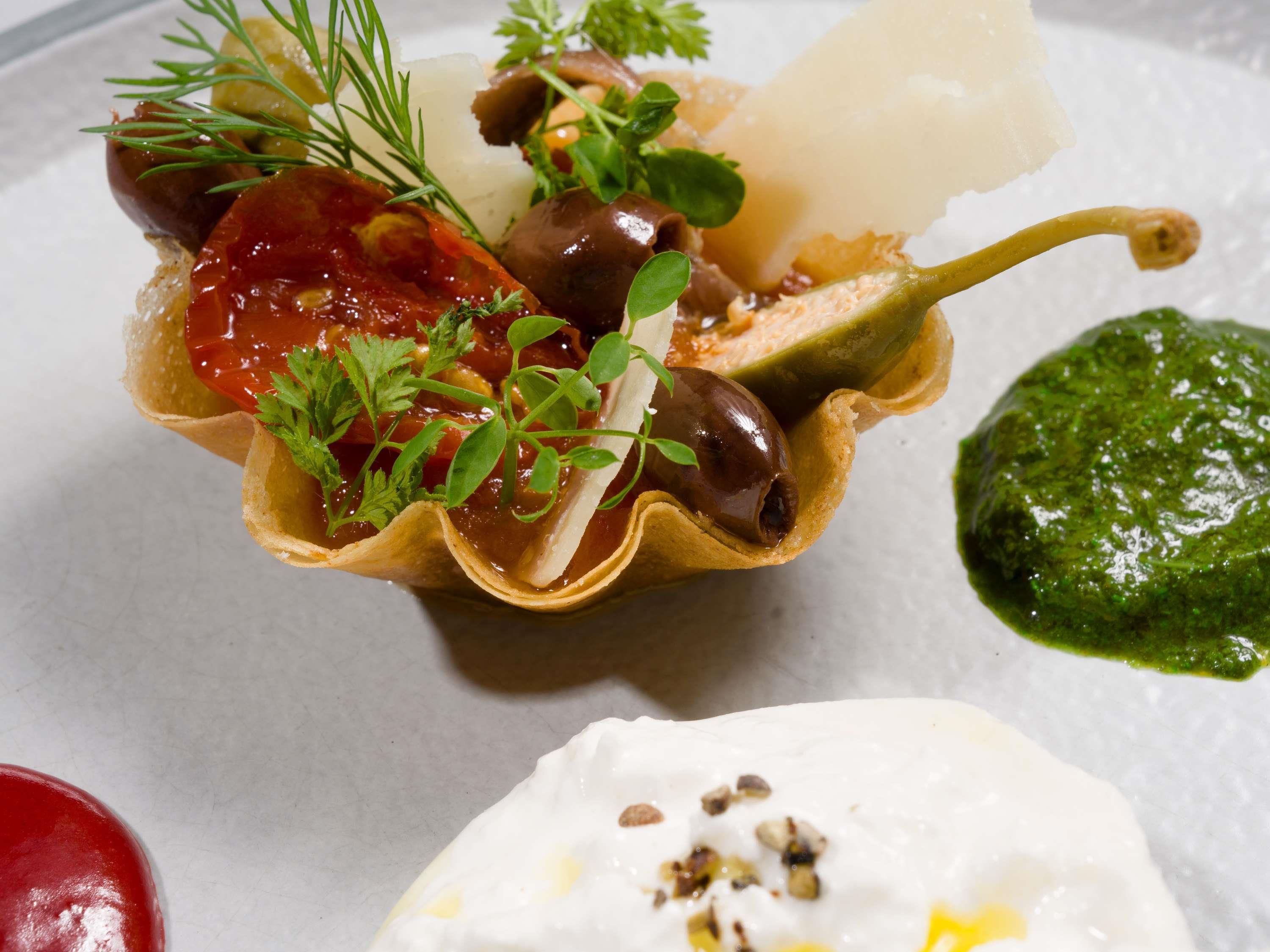 En ret med et fyldt grøntsagsfrugt, muligvis peberfrugt, pyntet med krydderurter og en klat sauce.