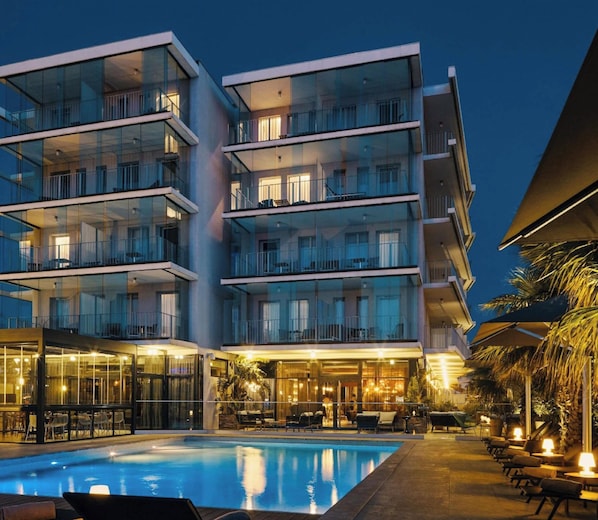 Ett hotell med flera våningar, en swimmingpool, utomhusplats och en väl upplyst fasad.