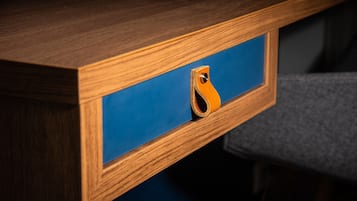 A wooden desk with a blue drawer and a leather strap.