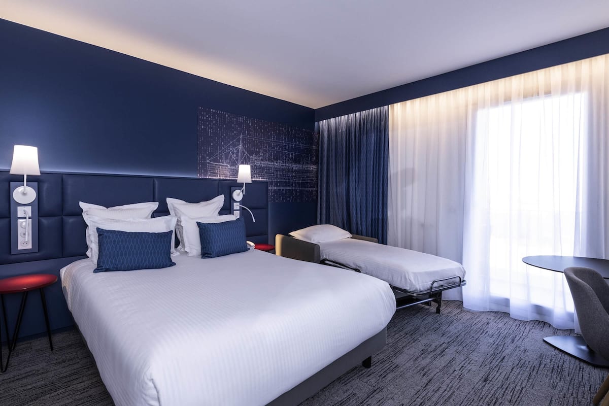 Une chambre d’hôtel avec un grand lit, deux tables de chevet, un bureau et une chaise.