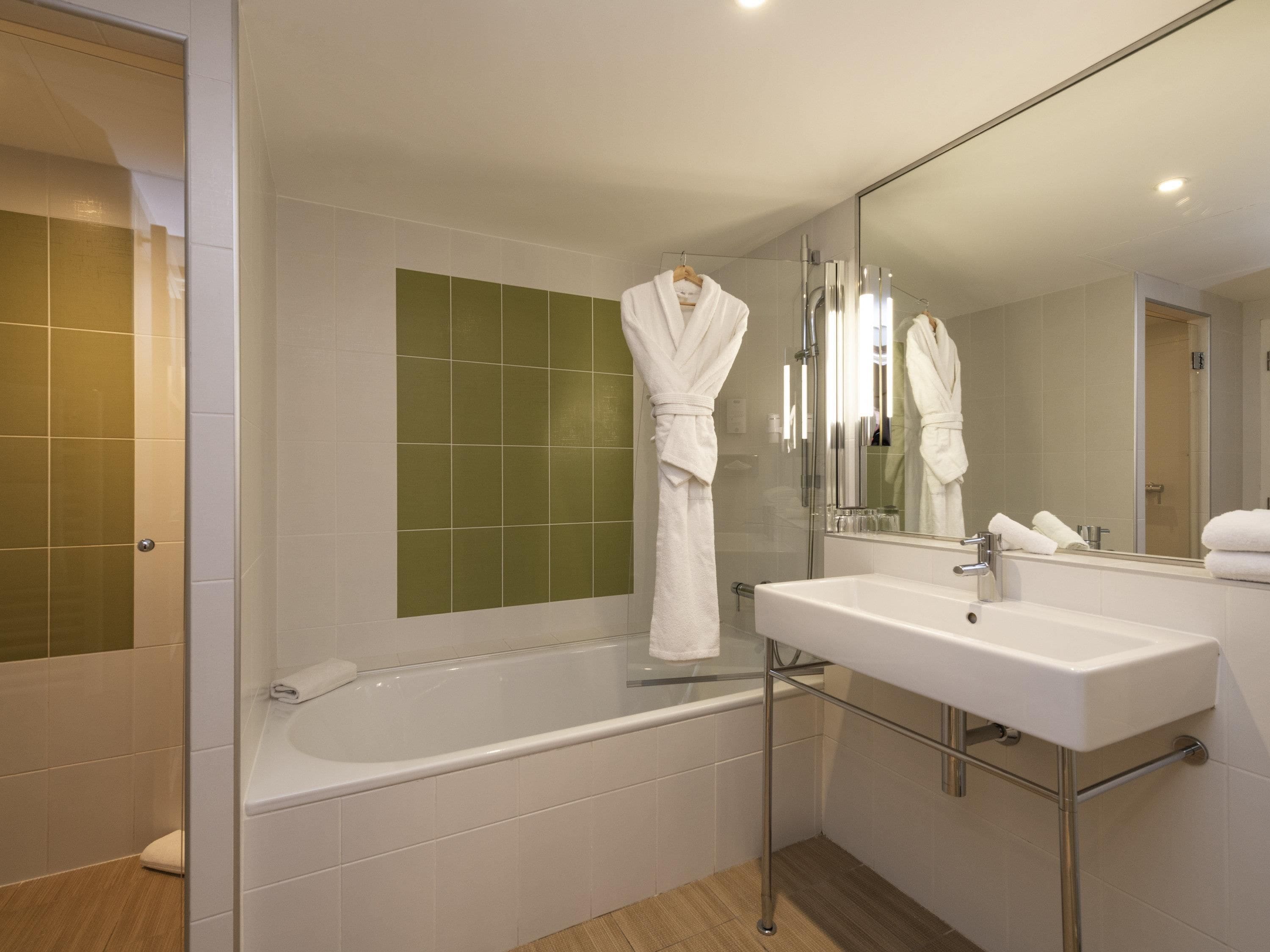 A modern bathroom with a bathtub, a sink, and a large mirror.