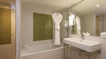 A modern bathroom with a bathtub, a sink, and a large mirror.