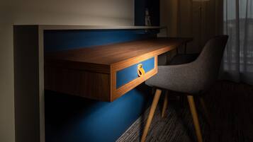 Een modern bureau met een ingebouwde lade, een stoel en een blauwe accentmuur.