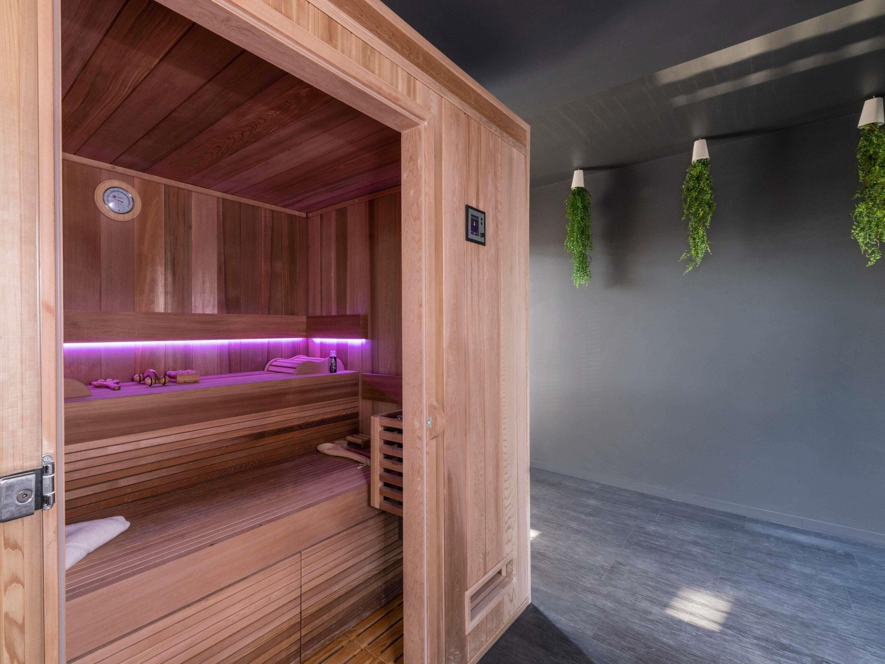 A wooden sauna with a bench, a wall-mounted heater, and a control panel.