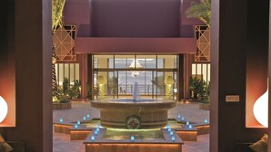 A reception area with a central fountain, seating, and a view of the sea. - Mövenpick Resort & Spa Tala Bay Aqaba (Aqaba)