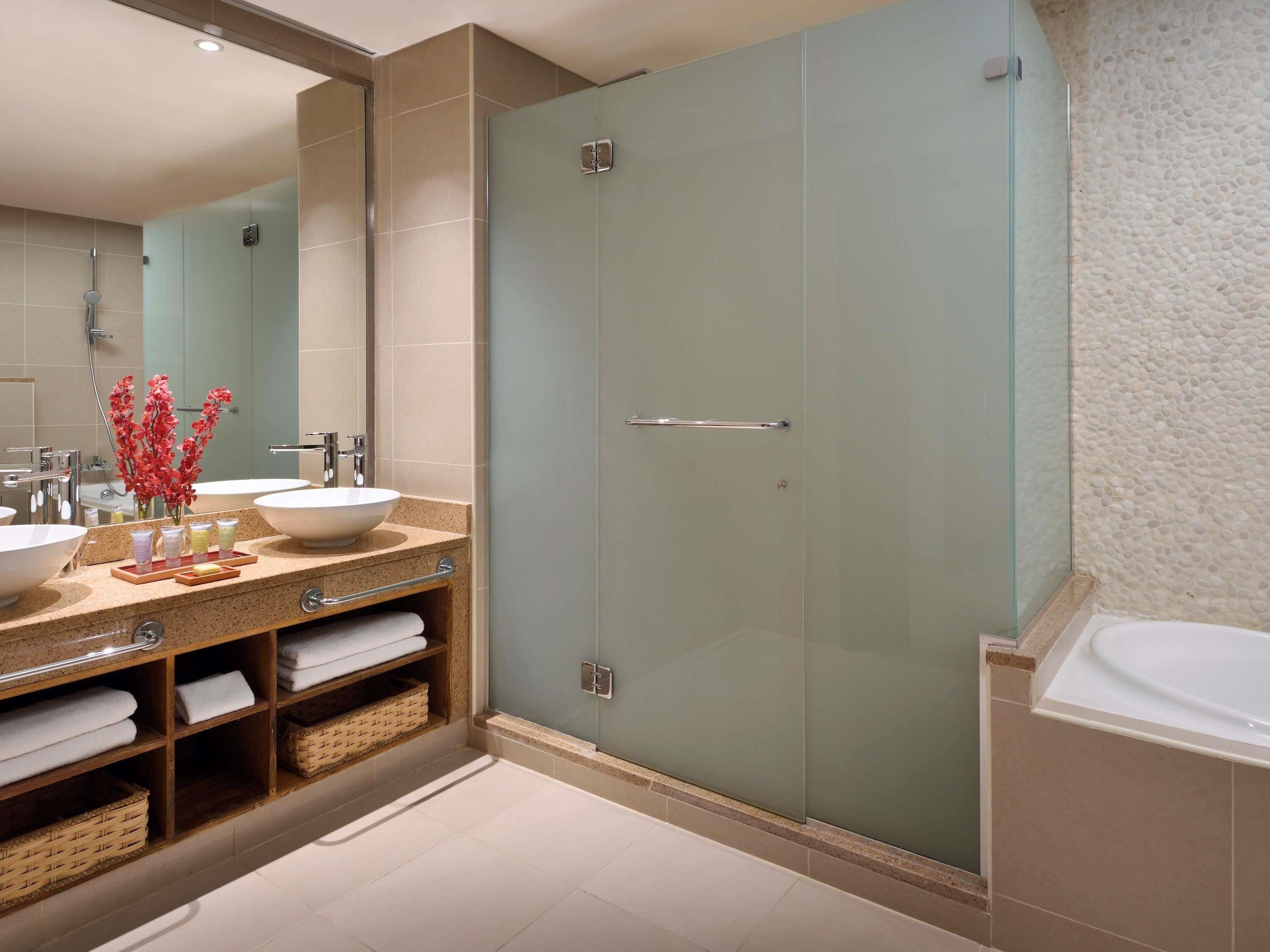 A modern bathroom with two sinks, a glass shower enclosure, and a bathtub.