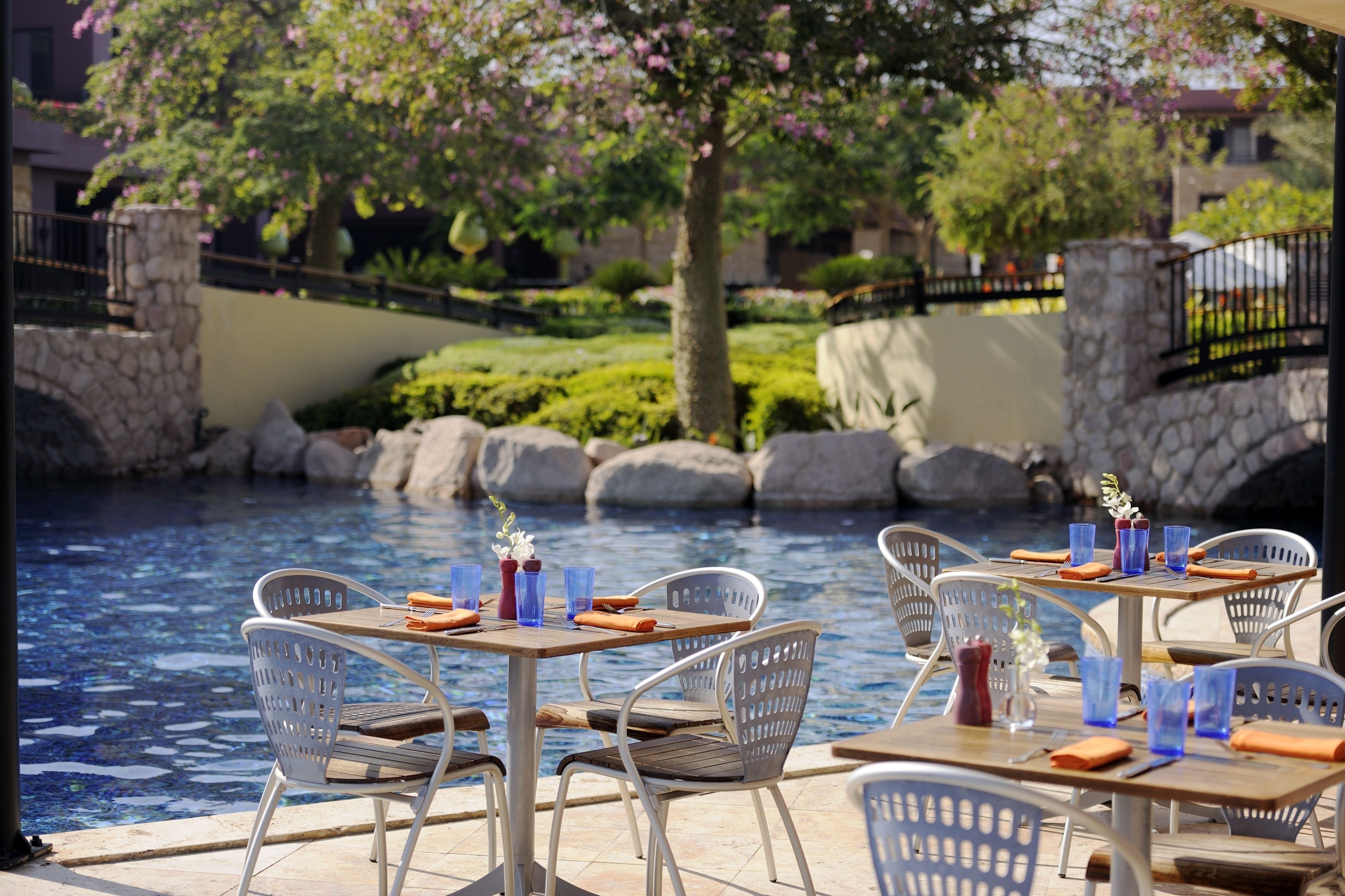 Outdoor seating by a pool with stone walls and greenery.
