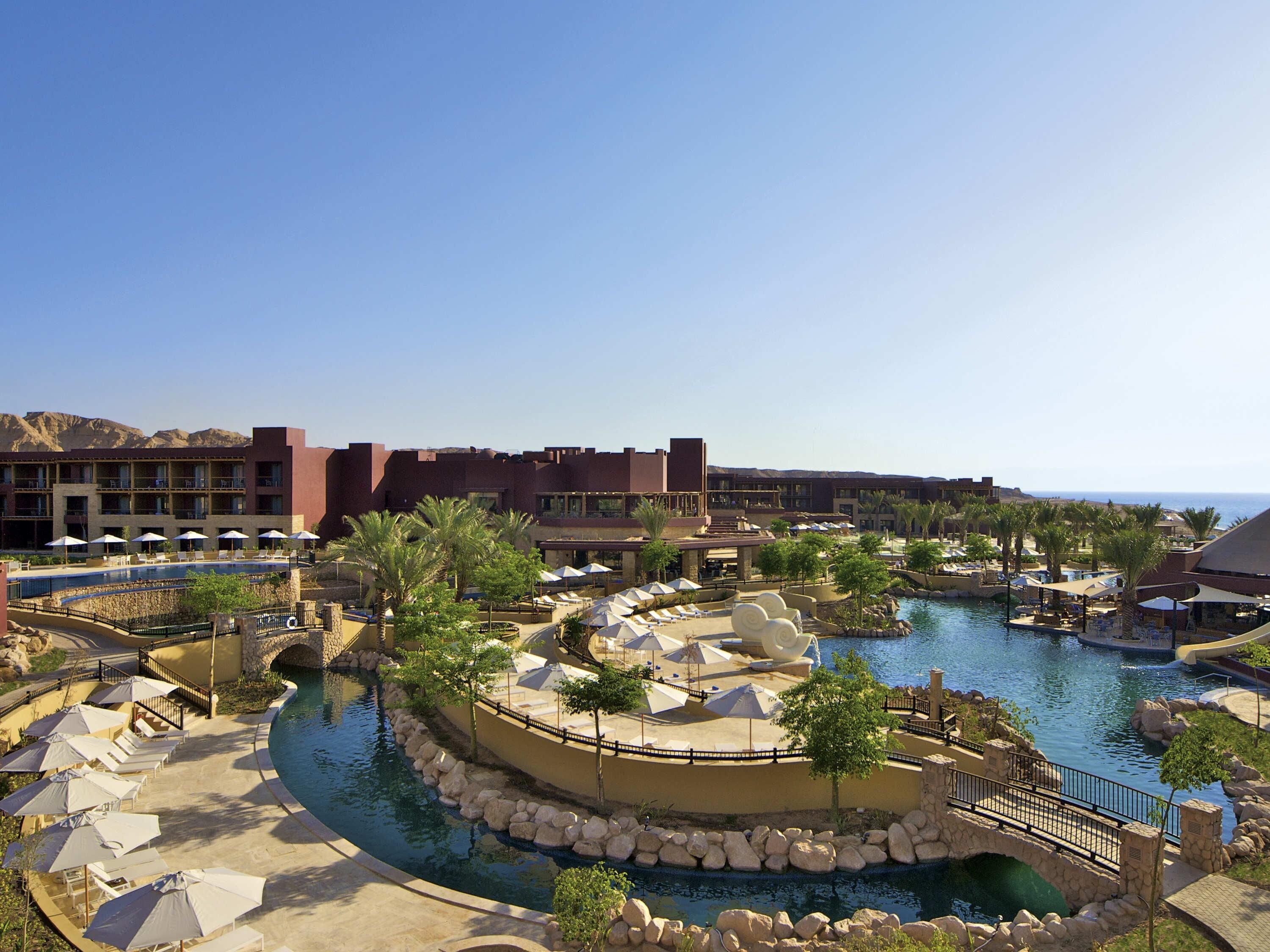 A resort with a pool, lounge chairs, and a view of the mountains.