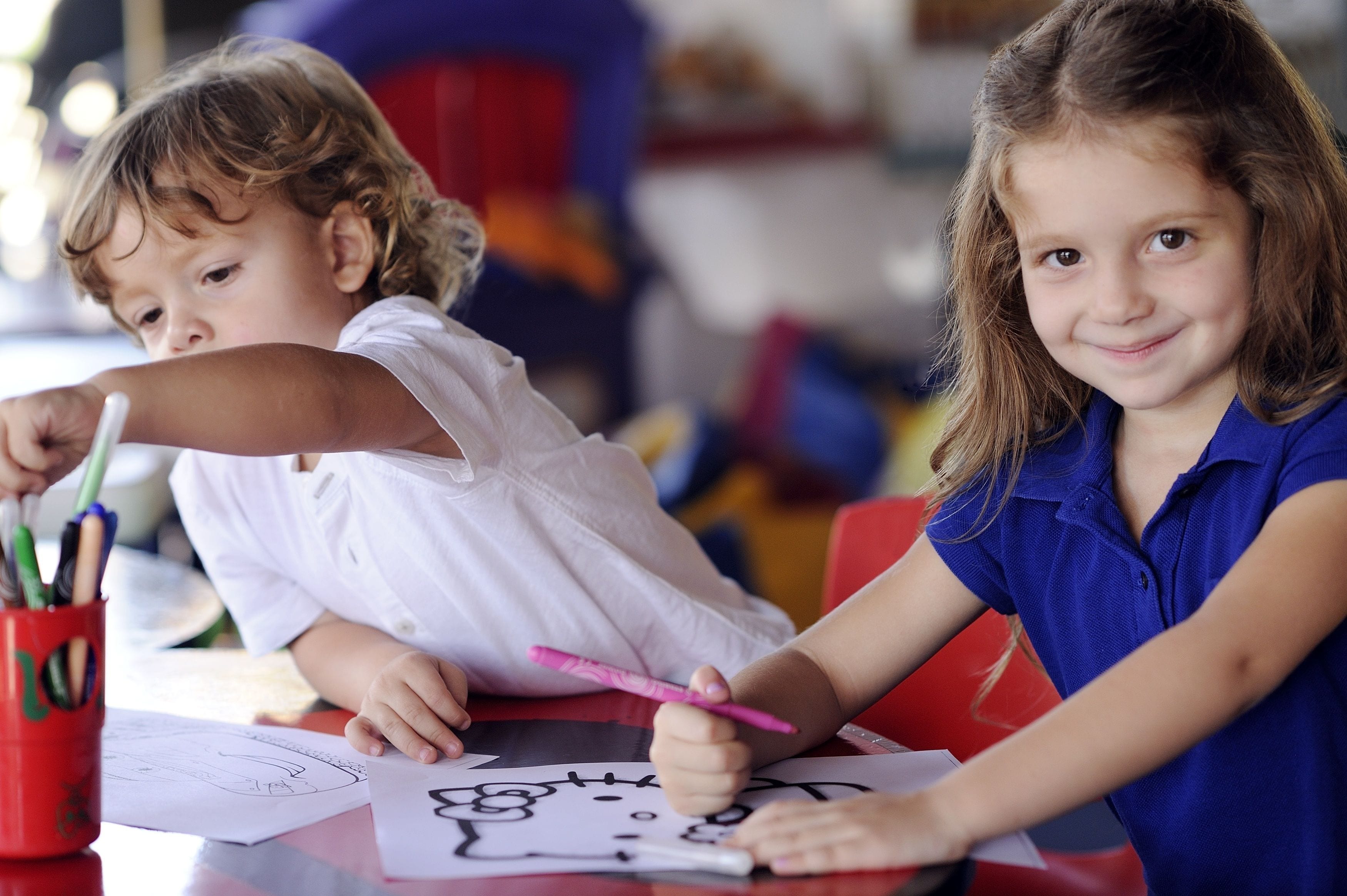 Due bambini che disegnano a un tavolo con materiale artistico.