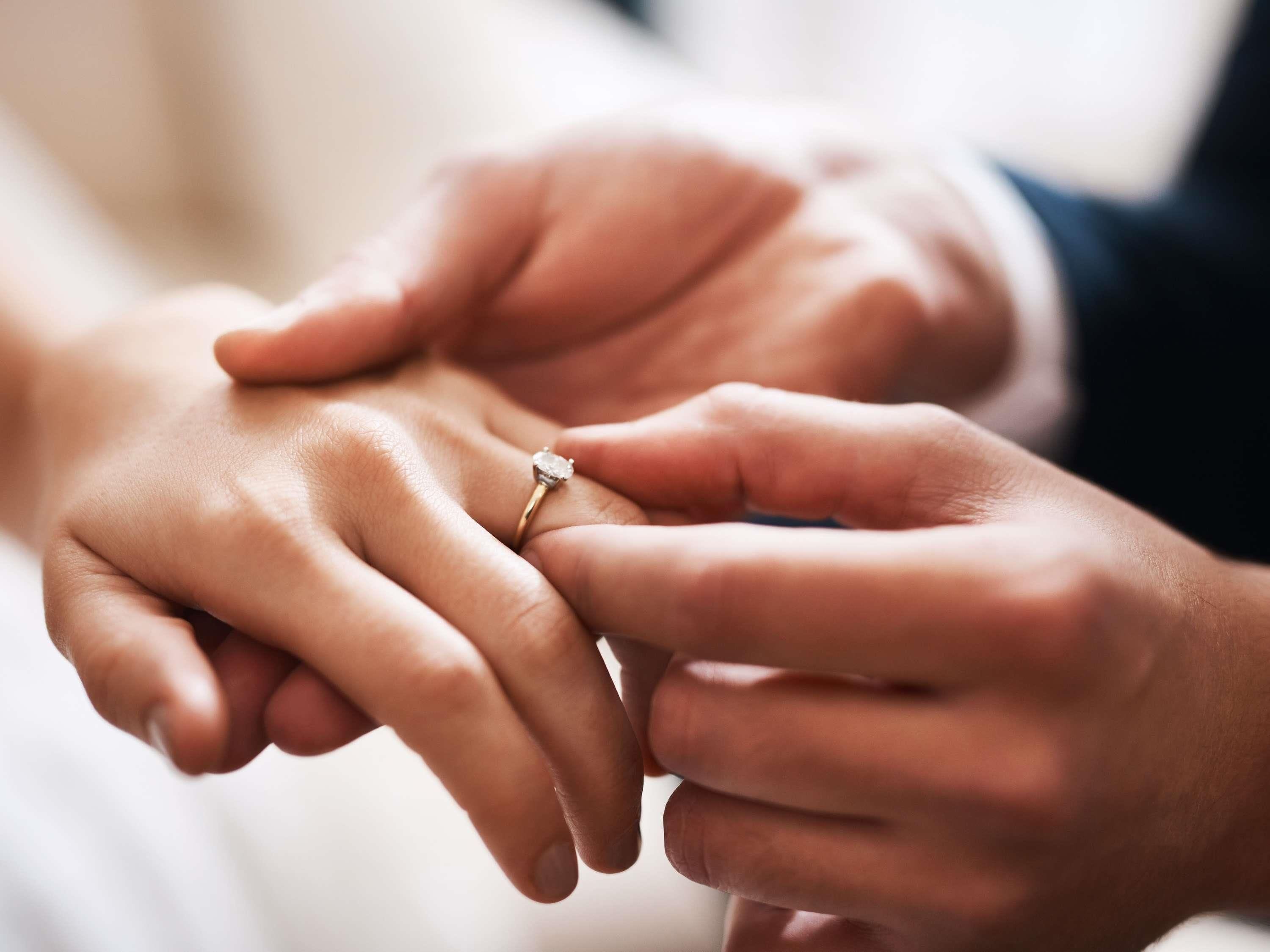 A close-up of hands exchanging a ring.
