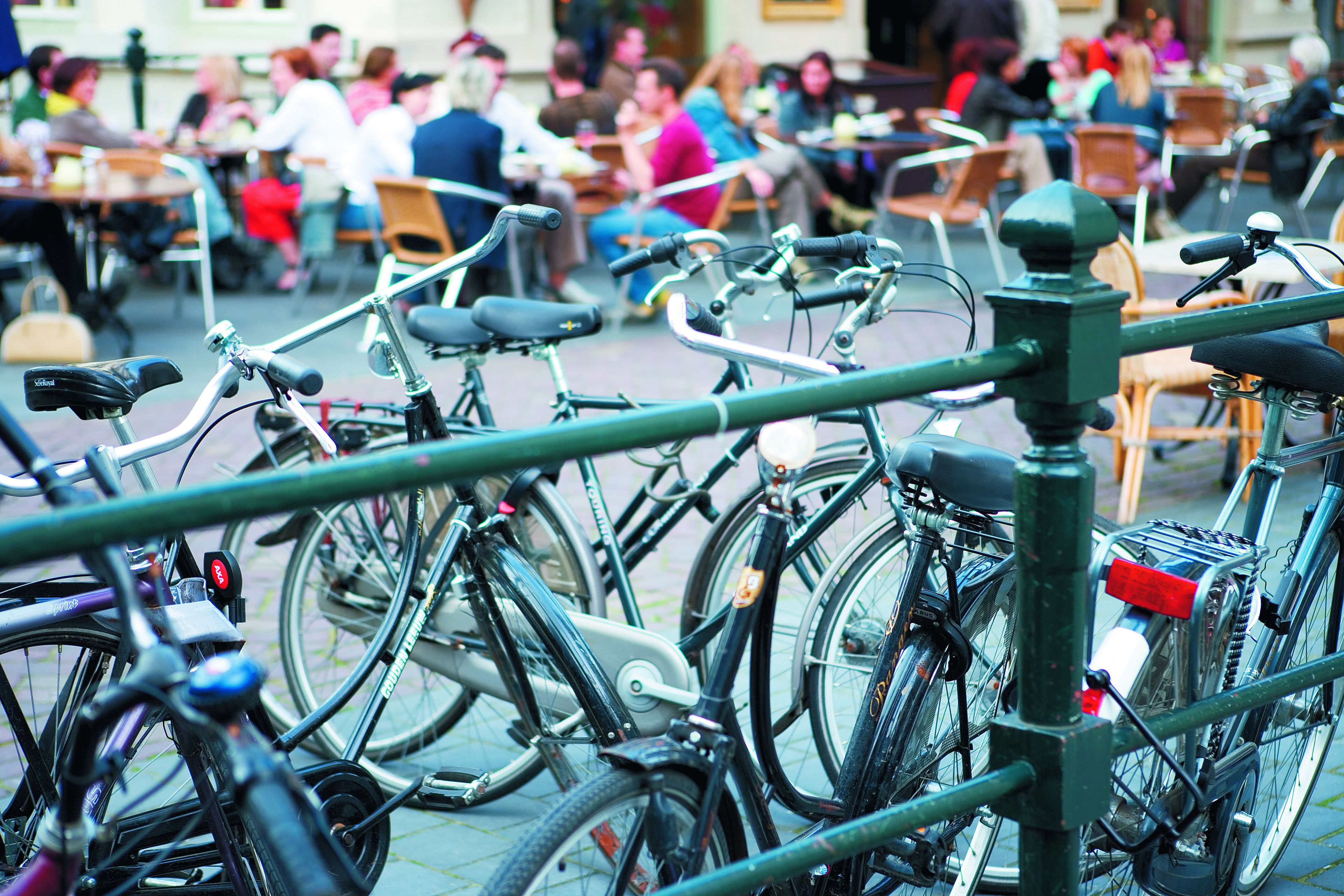 Bicycles parked in an outdoor seating area with tables and chairs.