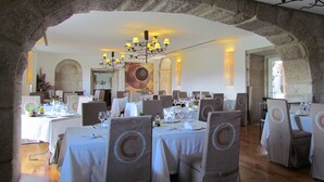 A restaurant with stone arches, white tablecloths, and grey chairs. - Convento dos Capuchos (Monção)