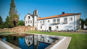 A large white building with a pool in front, surrounded by a well-maintained lawn and trees. - Convento dos Capuchos (Monção)