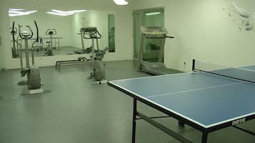 A gym with exercise equipment, a treadmill, and a ping pong table.