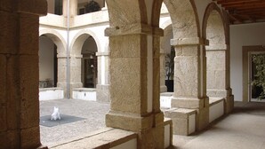 A courtyard with stone arches and columns, a fountain, and a potted plant. - Convento dos Capuchos (Monção)