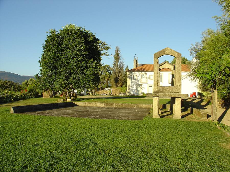 A historic building with a large archway, surrounded by well-maintained grassy areas and trees.