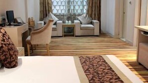 Habitación de hotel con cama, escritorio con ordenador, silla, sofá y alfombra estampada.