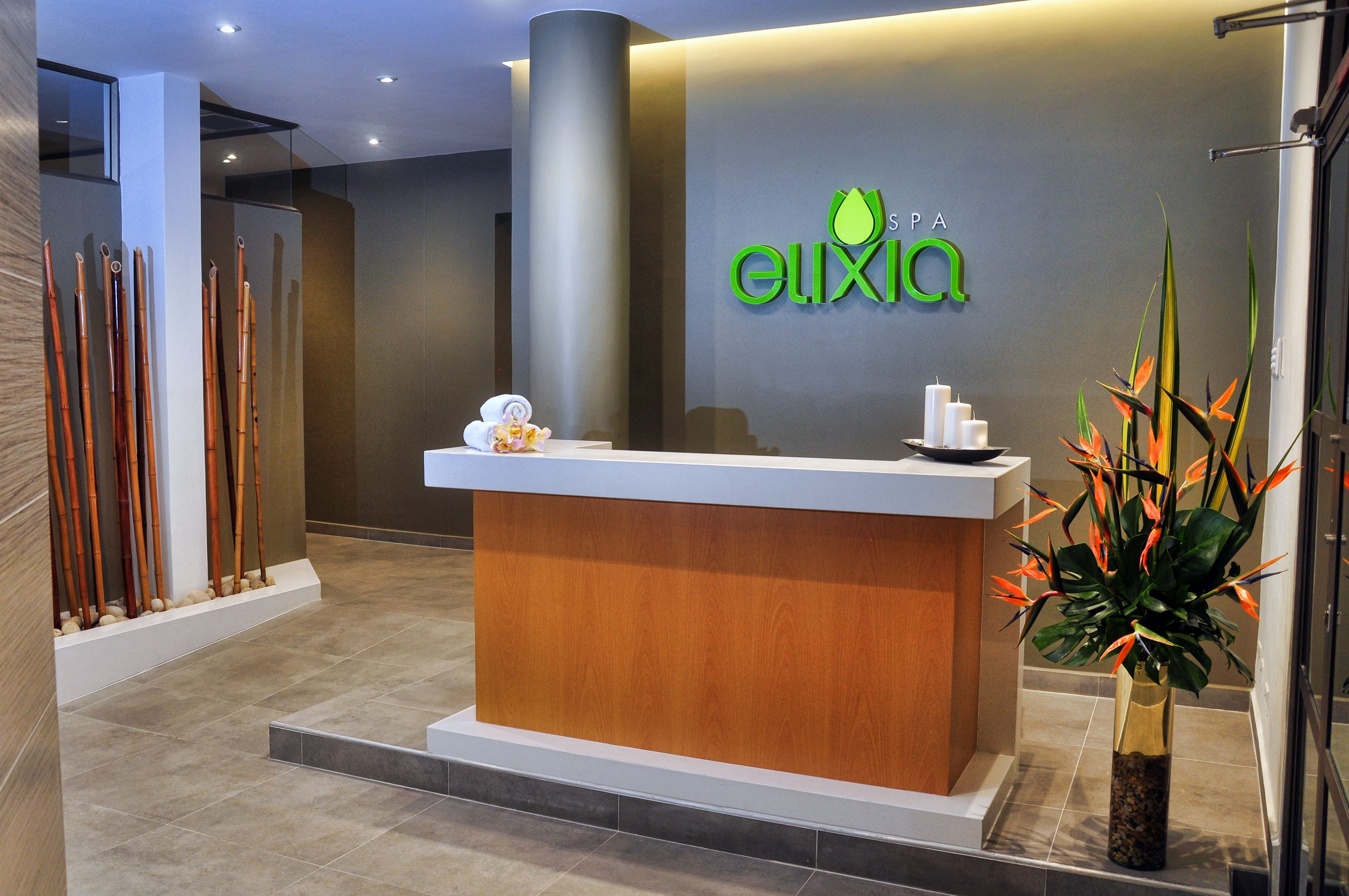 A reception desk with a logo, a plant, and a row of wooden sticks.