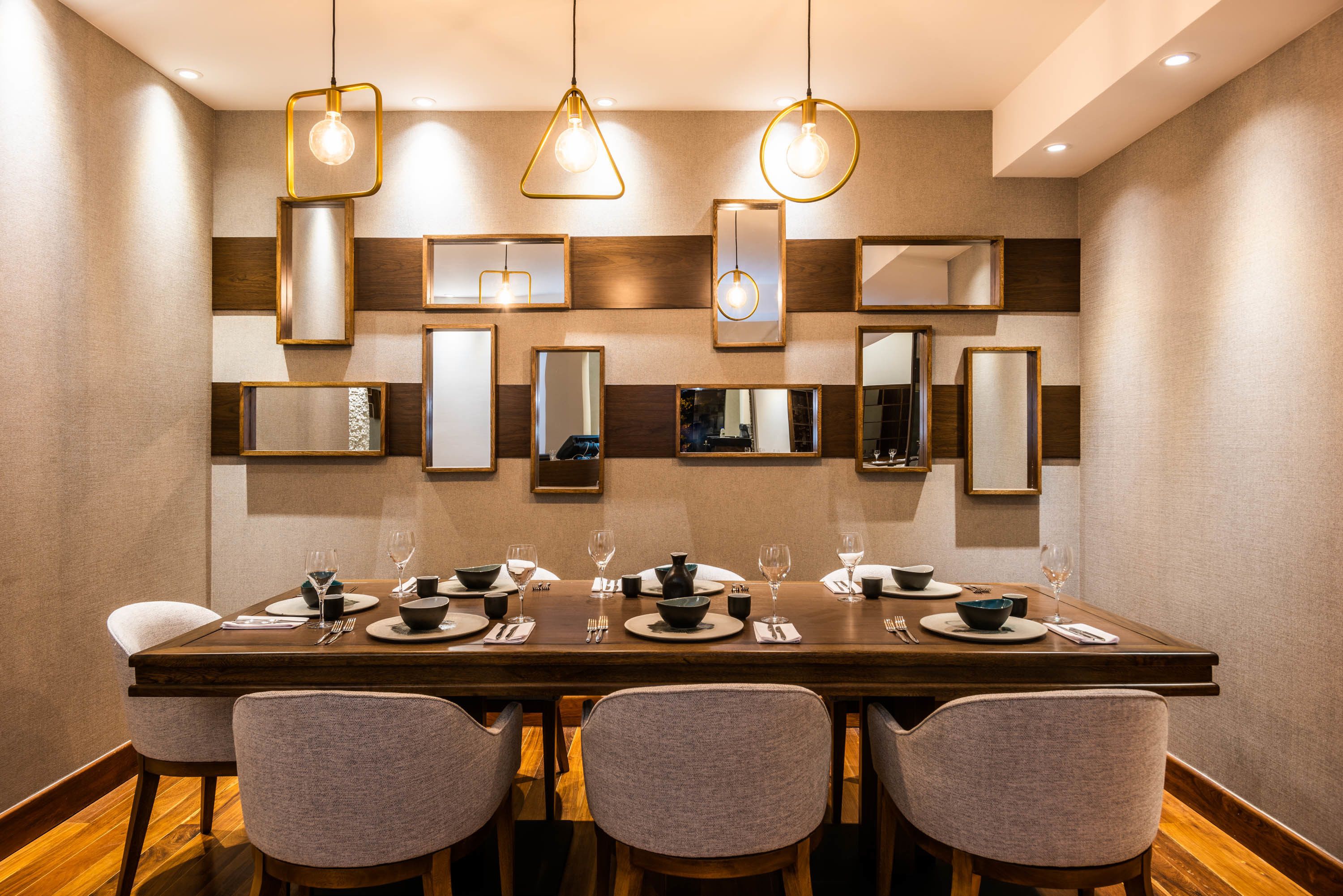 Un espace repas avec une longue table, de nombreuses chaises et des lampes suspendues.