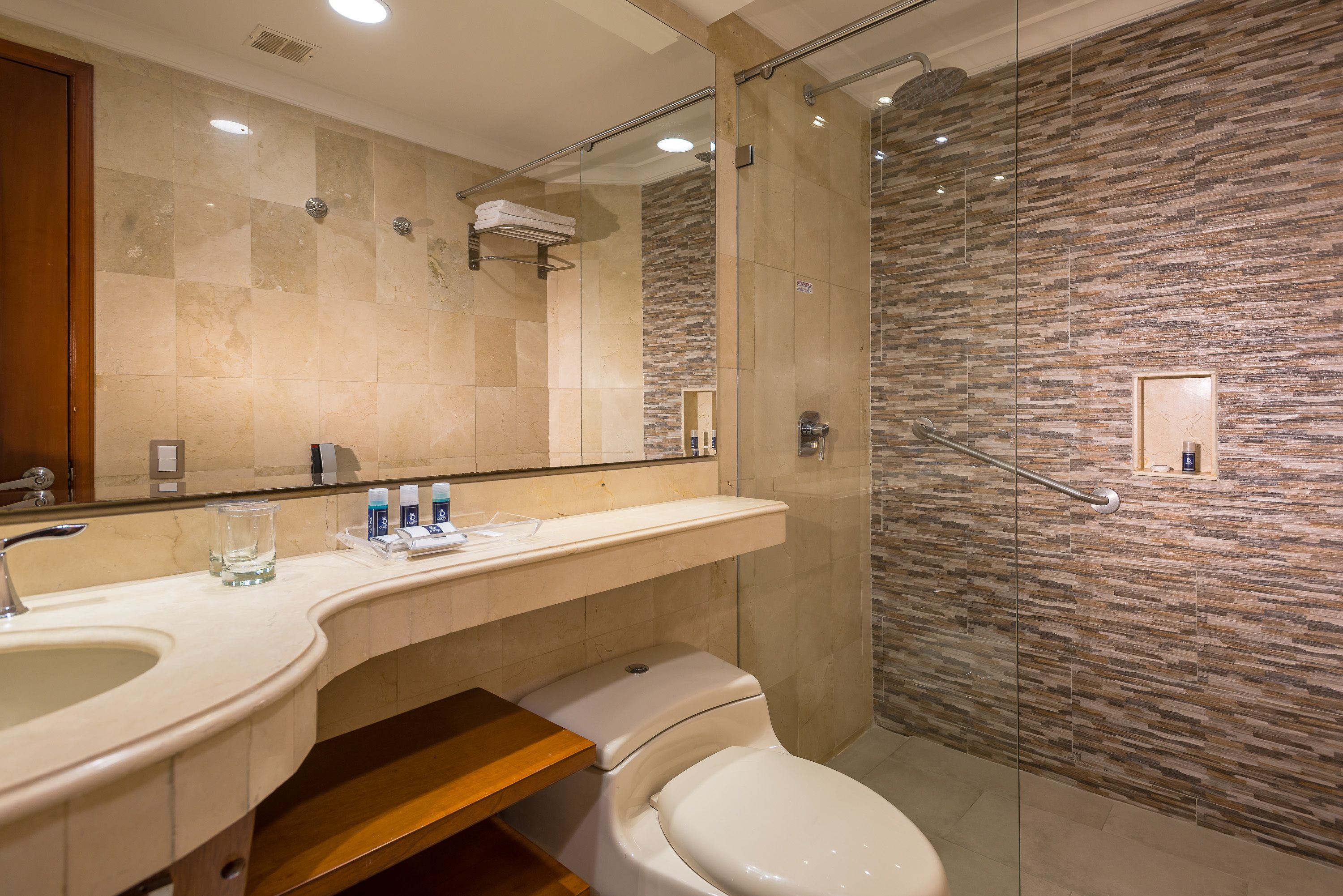 A modern bathroom with a glass-enclosed shower, a large mirror, and a vanity with a sink and countertop.