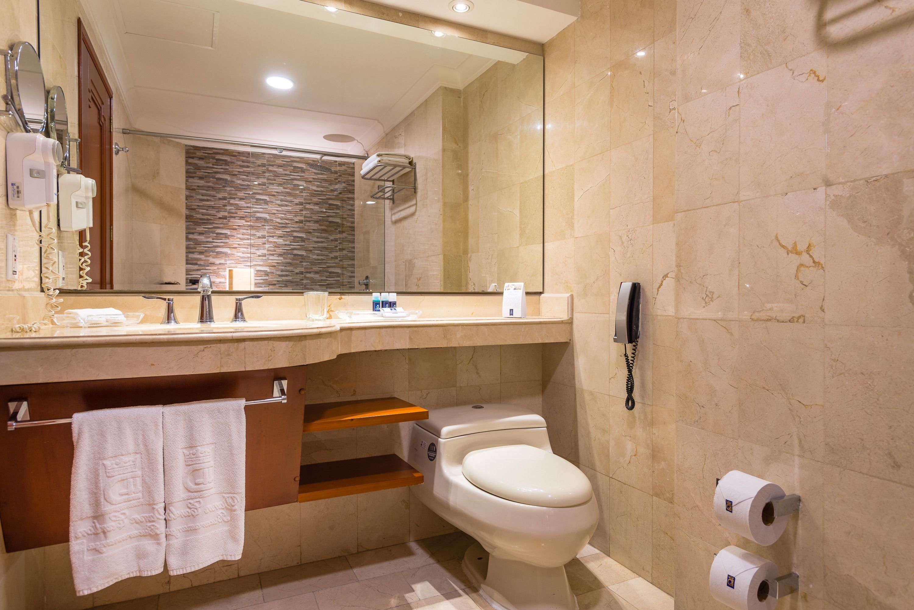 A modern bathroom with a vanity, a toilet, a shower, and a telephone.