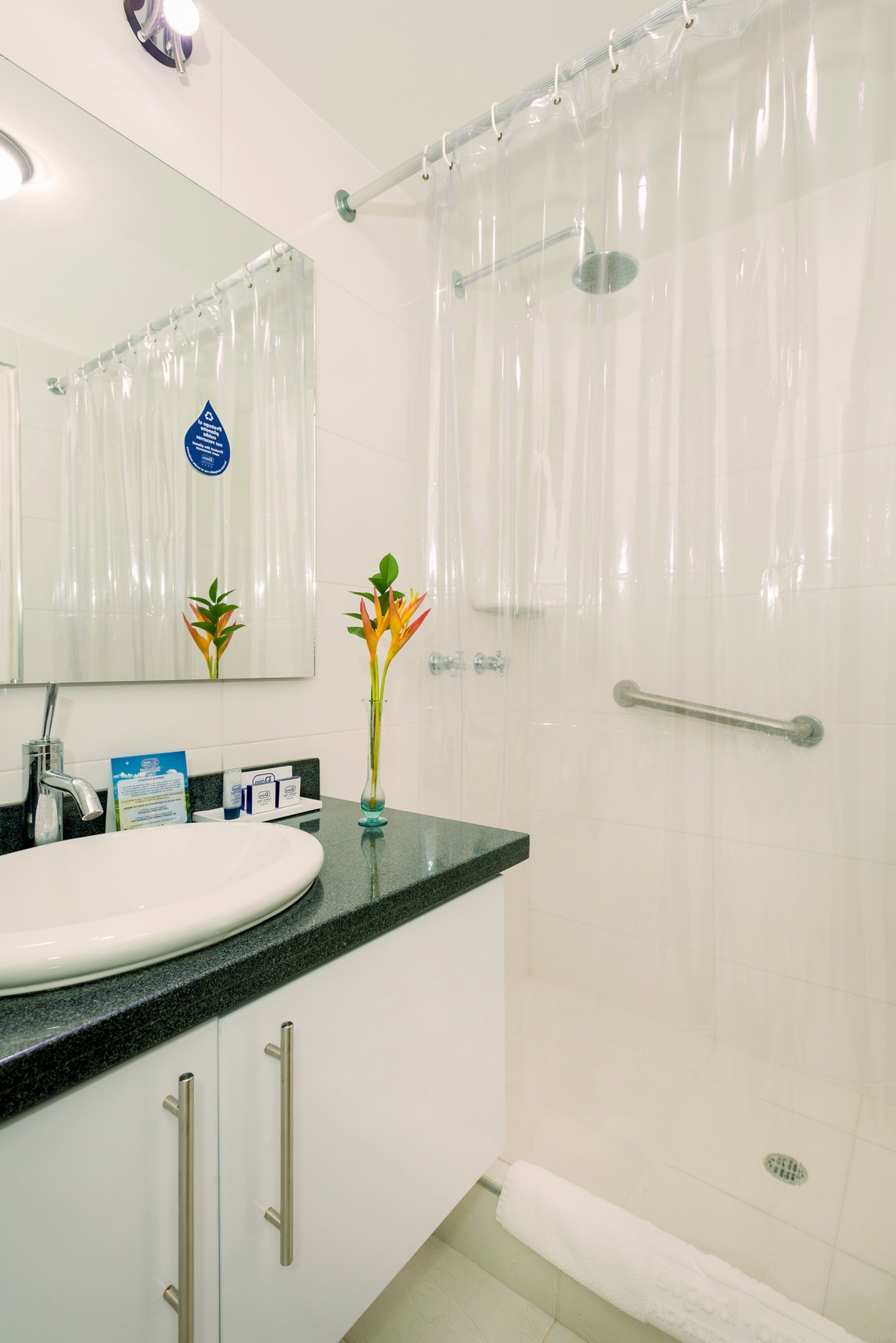 A bathroom with a white sink, a mirror, a shower curtain, and a towel rack.