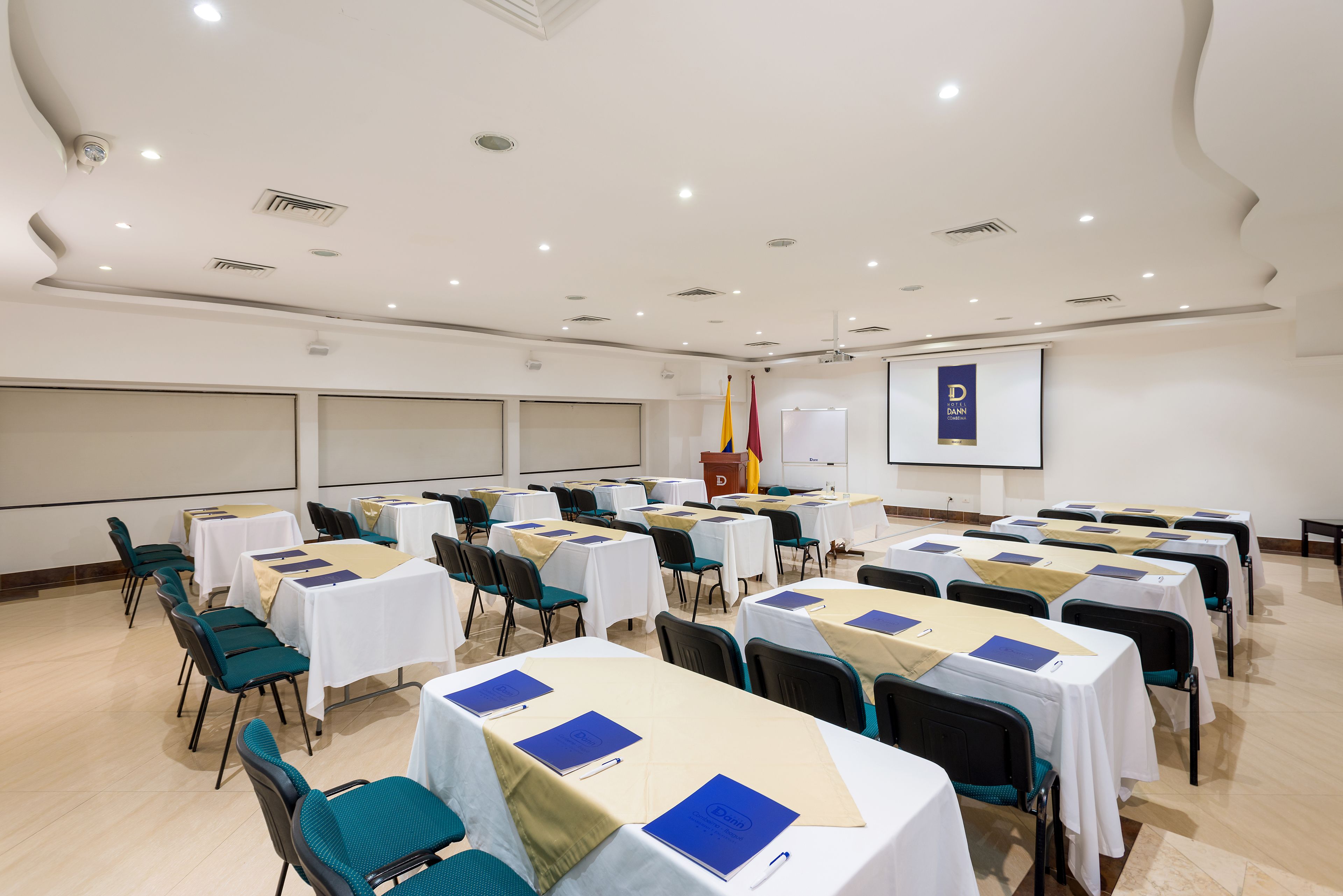 A conference room with tables and chairs, a podium, and a projection screen.