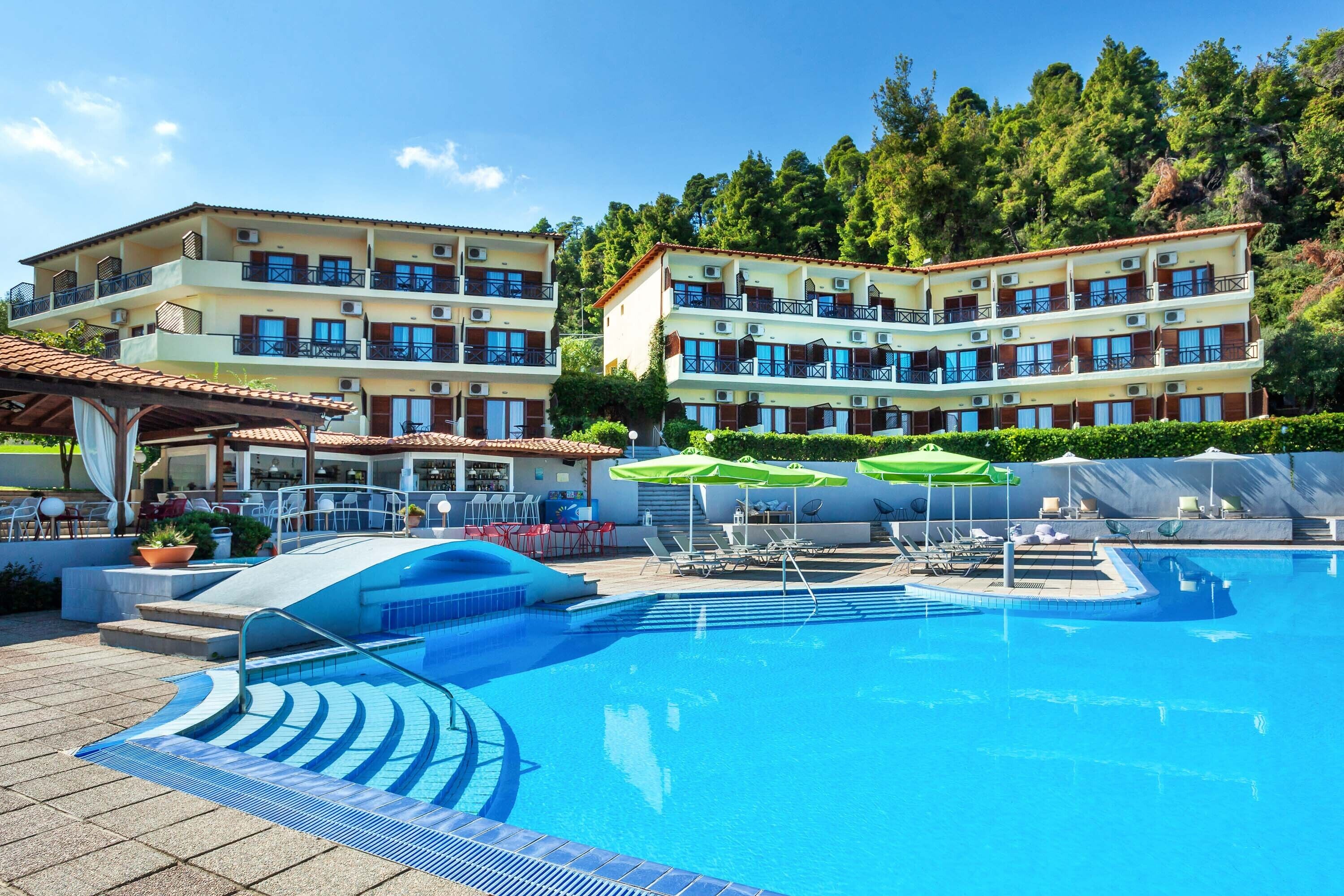 Un hôtel doté d’une piscine, d’un espace extérieur aménagé et offrant une vue sur une colline boisée.