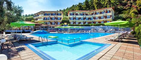 Ein Poolbereich mit Liegestühlen und Sonnenschirmen, umgeben von mehrstöckigen Gebäuden mit Balkonen.