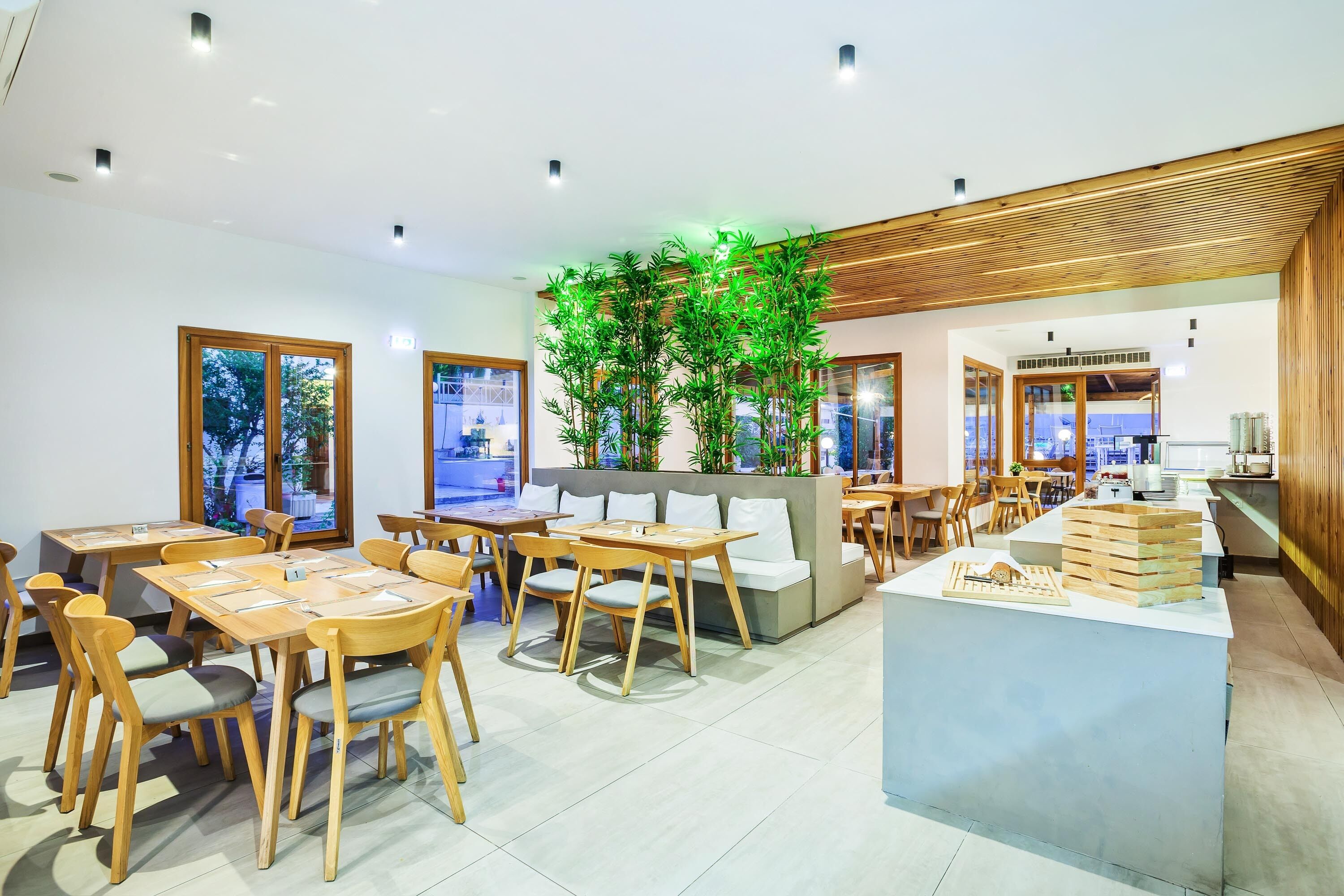 A modern cafe with wooden furniture, a central plant, and a counter with a menu display.