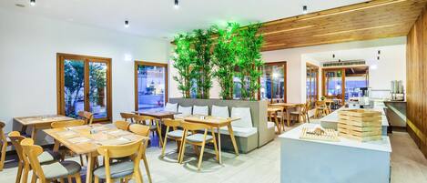 A modern cafe with wooden furniture, a central plant, and a counter with a menu display.