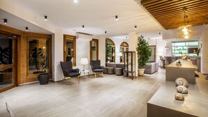 A spacious living area with a wooden ceiling, a central island with decorative shells, and a seating area with modern chairs and a lamp. - Palladium Hotel (Kassandra)
