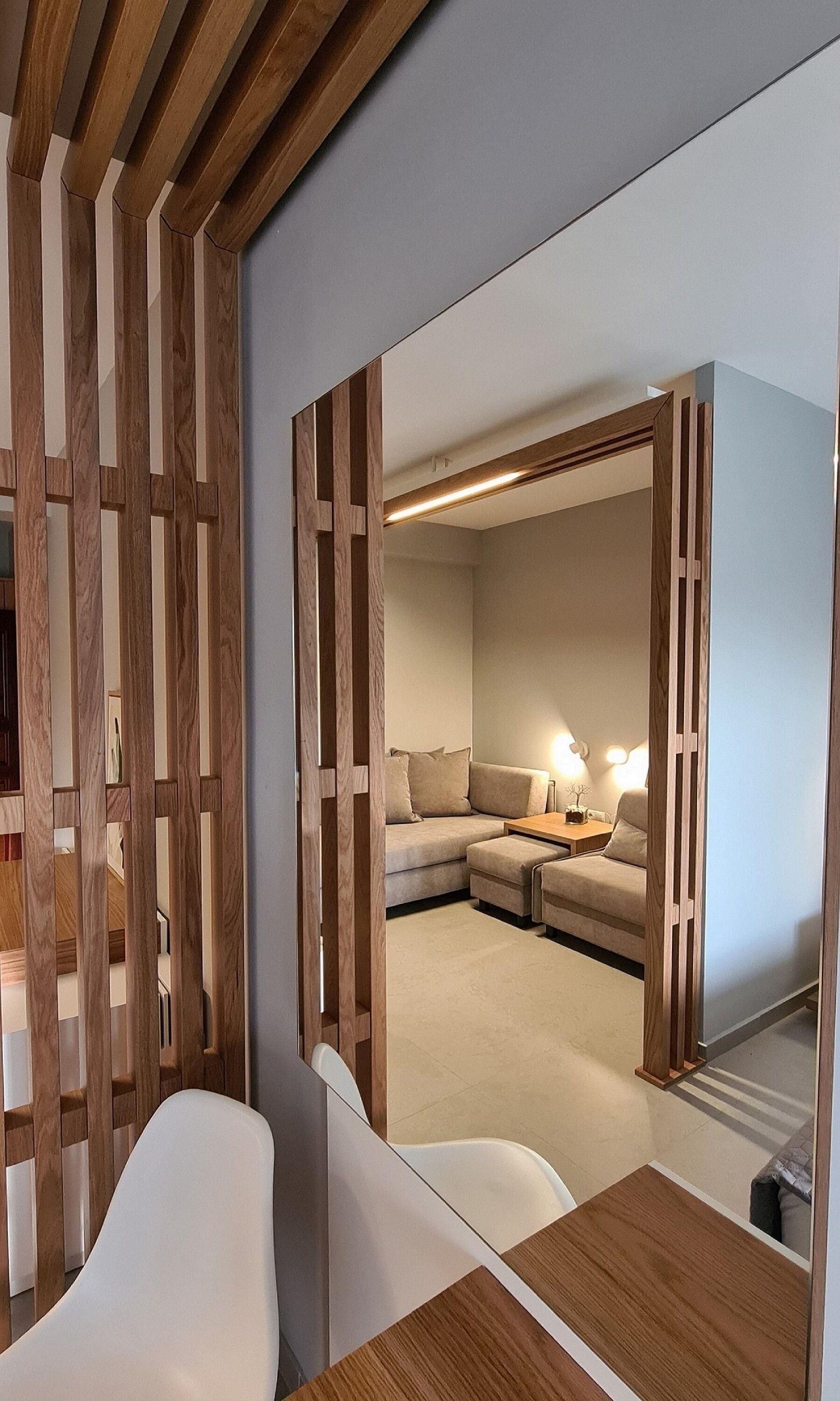 A modern interior with a wooden partition, a sofa, a table, and a lamp.