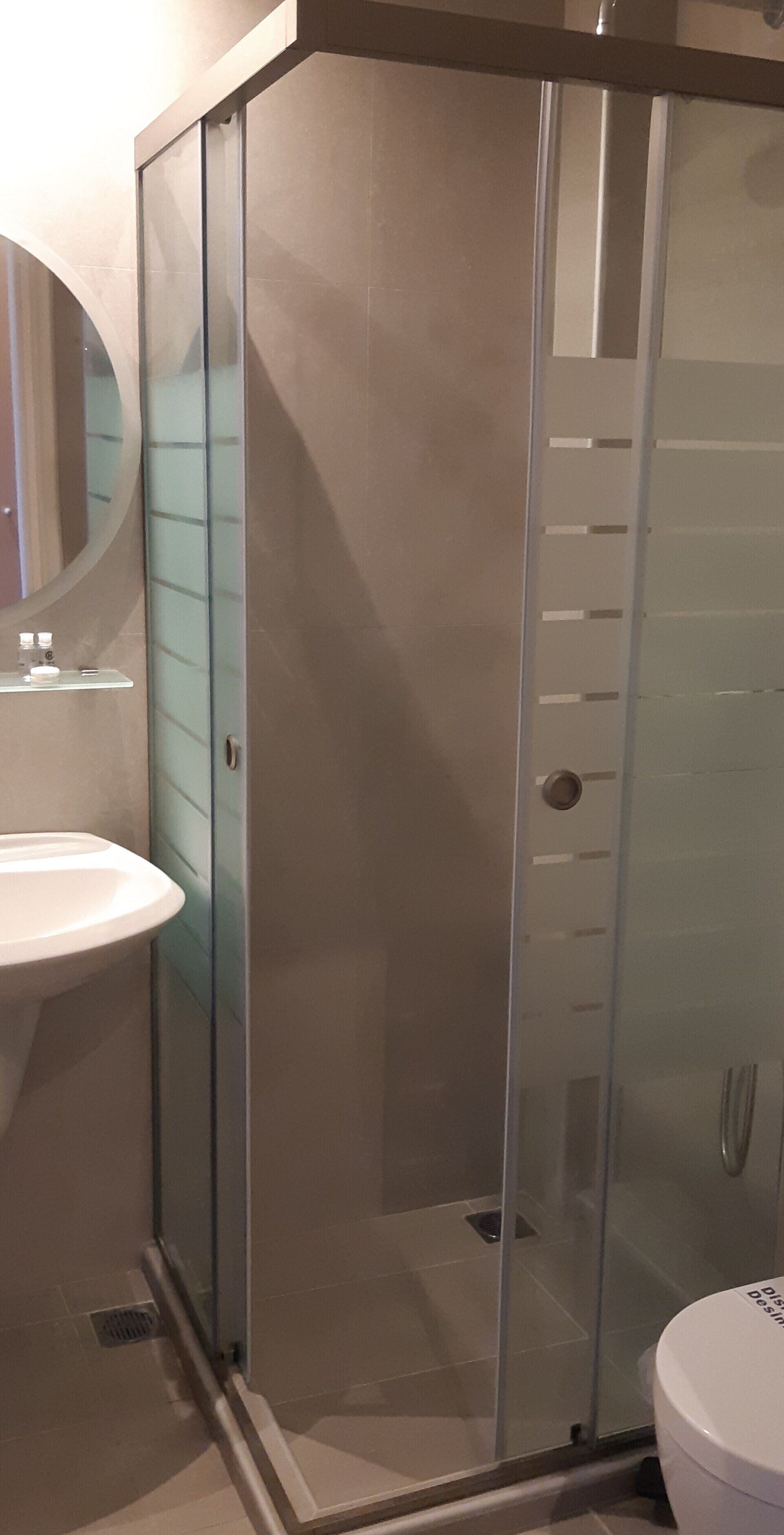 A modern bathroom with a glass shower enclosure, a white sink, and a toilet.