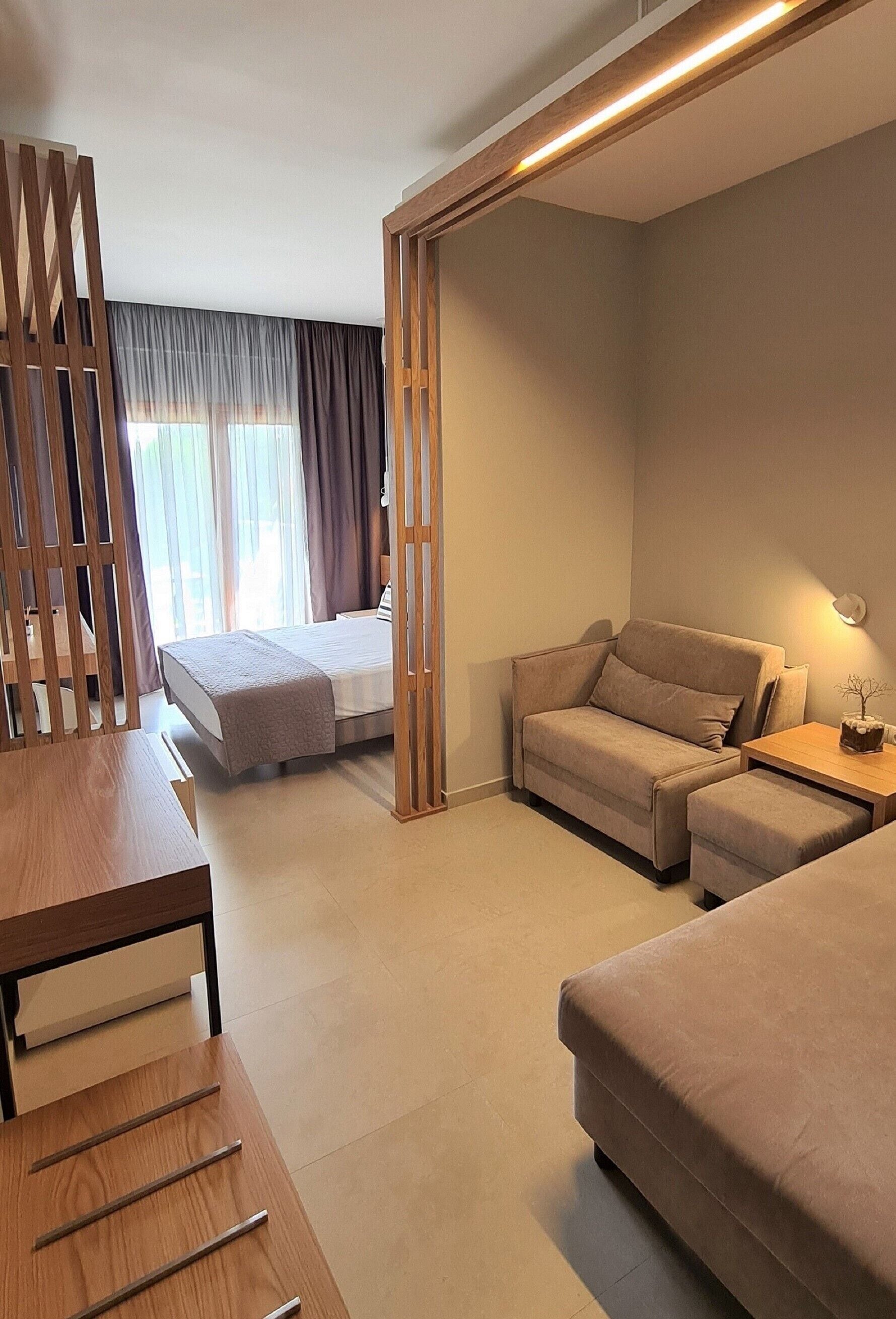 Una habitación de hotel moderna con una cama, un sofá, un escritorio y un separador.