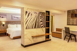 A modern hotel room with a bed, a desk, and a chair. There is a large wall art piece and a decorative wall panel. - Gamma Ciudad Juarez (Ciudad Juárez)