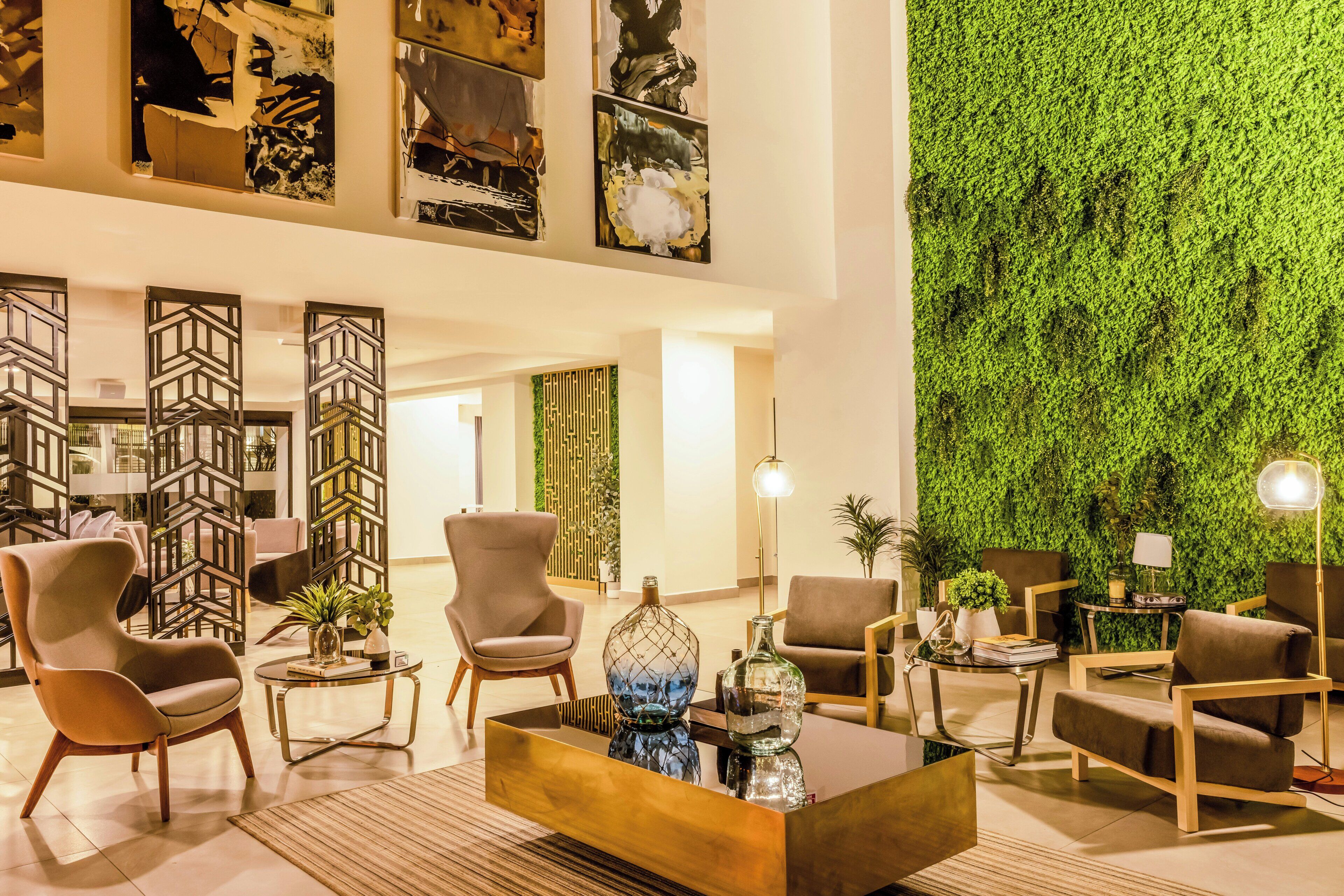 A modern lobby with contemporary furniture, a green wall, and abstract art.