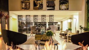 A modern living room with a central fireplace, comfortable seating, and decorative wall art. - Gamma Ciudad Juarez (Ciudad Juárez)