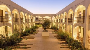 A courtyard with a central planter, surrounded by arches and a tiled walkway. - Gamma Ciudad Juarez (Ciudad Juárez)