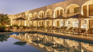 A poolside area with lounge chairs and umbrellas, reflecting the building's architecture. - Gamma Ciudad Juarez (Ciudad Juárez)