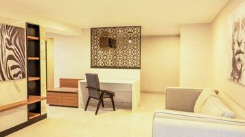 Quarto moderno com escrivaninha branca, cadeira preta, sofá branco e painel decorativo na parede.