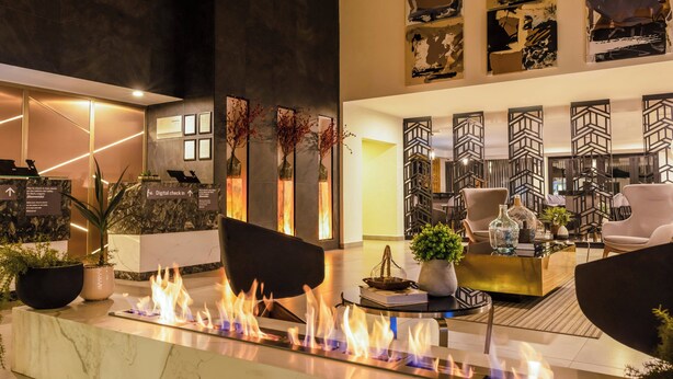 A modern lobby with a digital check-in desk, a fire feature, and contemporary furniture. - Gamma Ciudad Juarez (Ciudad Juárez)