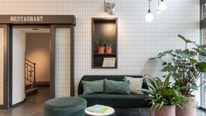 A modern interior with a green sofa, a small round table, and potted plants. - Alpenblick Bern (Bern)