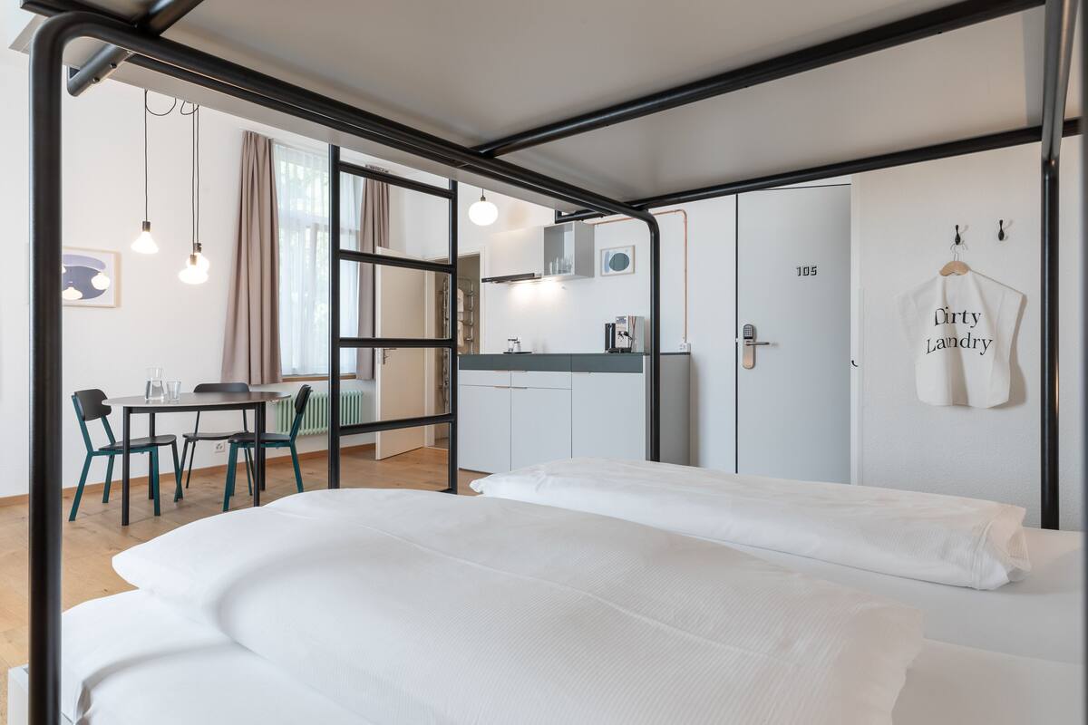 Ein modernes Hotelzimmer mit Bett, Schreibtisch und einer Küchenzeile.