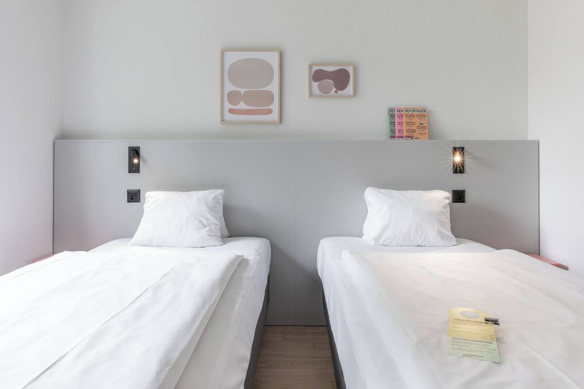 Ein Hotelzimmer mit zwei Einzelbetten, einem Kopfteil und einem kleinen Tisch mit einer Speisekarte.