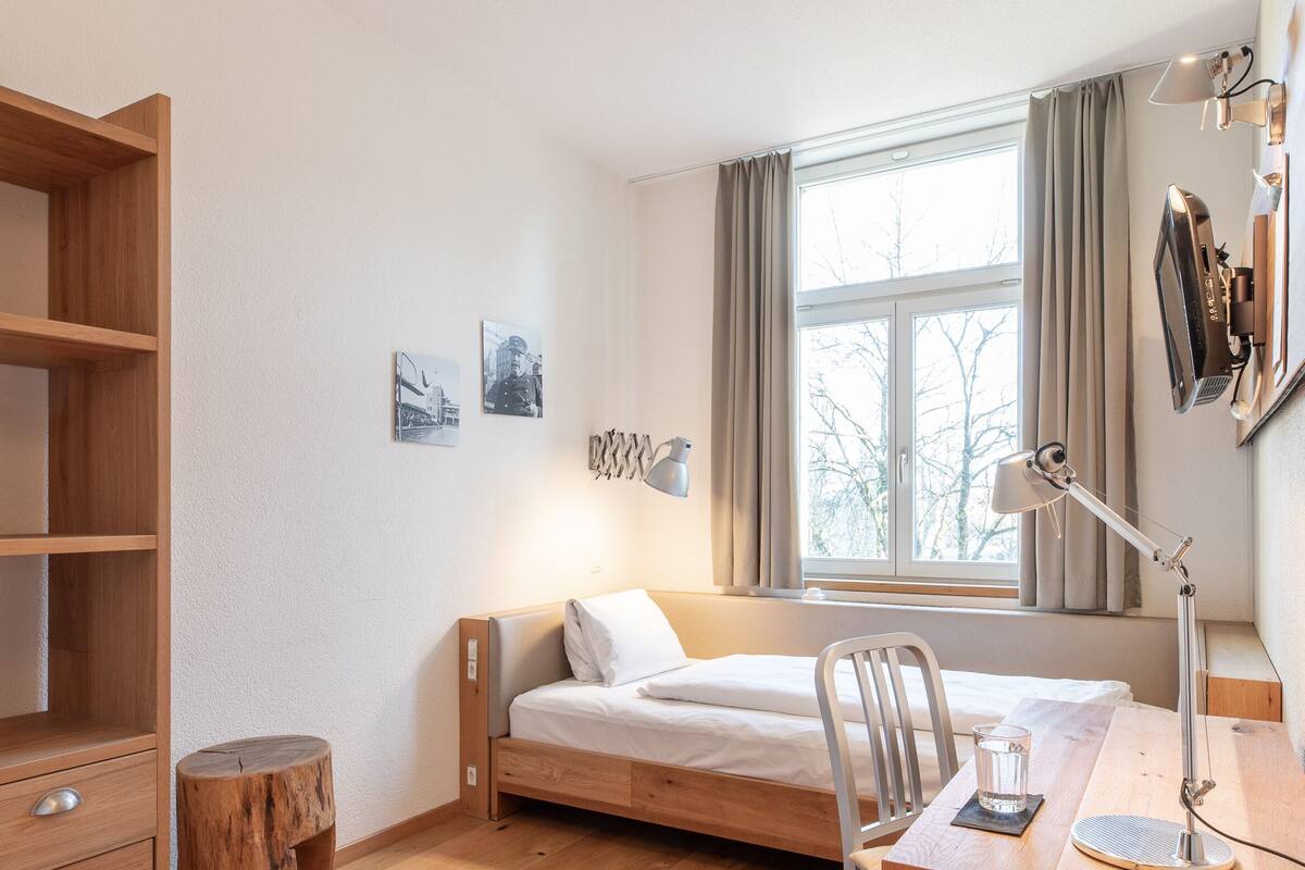 Ein Schlafzimmer mit einem Bett, Schreibtisch, Stuhl und einem Holzschrank.