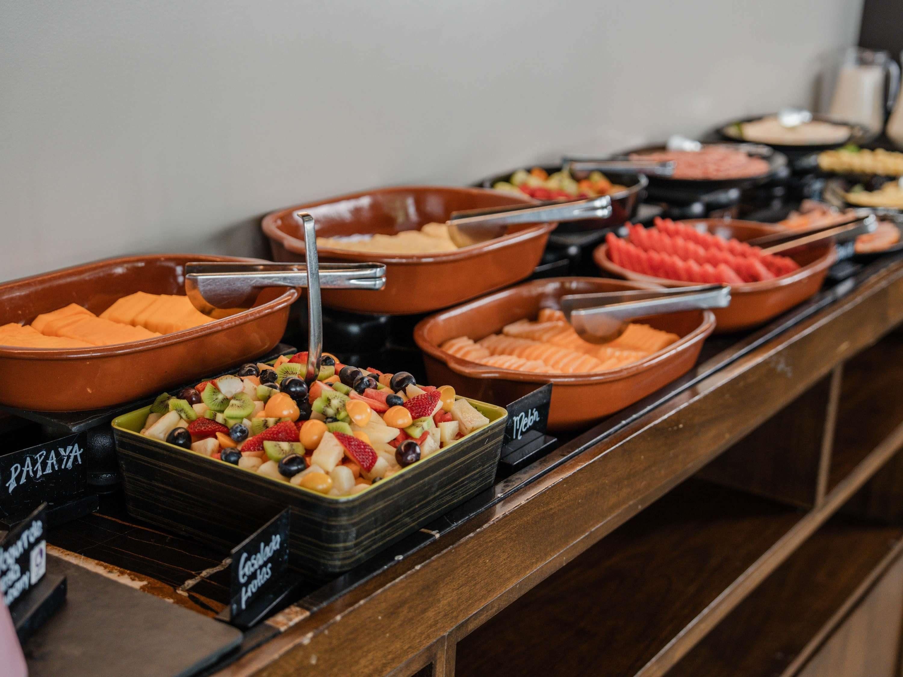 A buffet with various food options including fruits and meats.